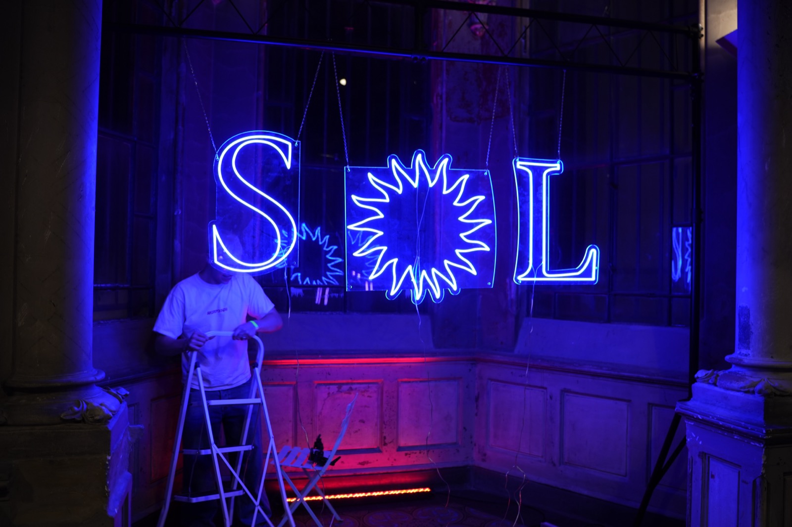 Blau leuchtender SOL Neon-Schriftzug beim Aufbau eines Events